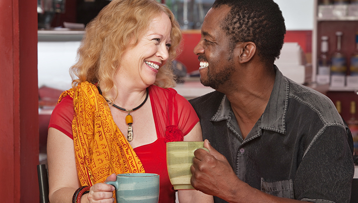 couple smiling at each other and holding coffee cups