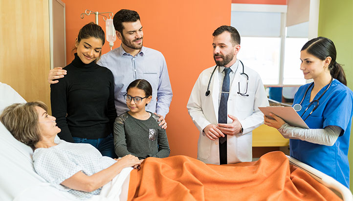 Family and two doctors at a patients bedside in hospital