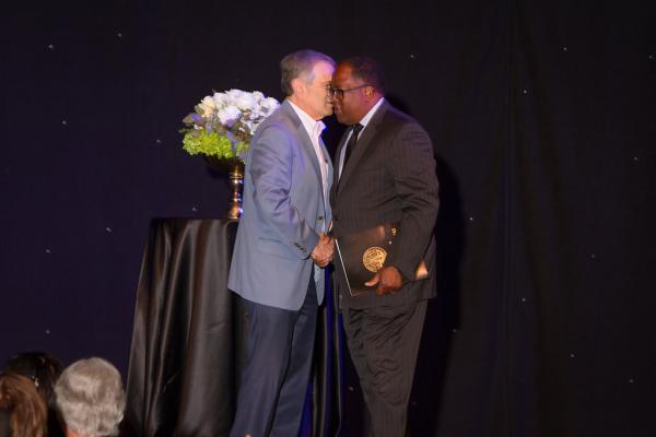 Two men shaking hands on stage at Man speaking at Spirit of Innovation Gala 2018