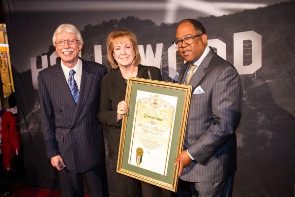 Group of Spirit of Innovation Gala attendees holding County of Los Angeles Commendation Award in front of Hollywood sign backdrop