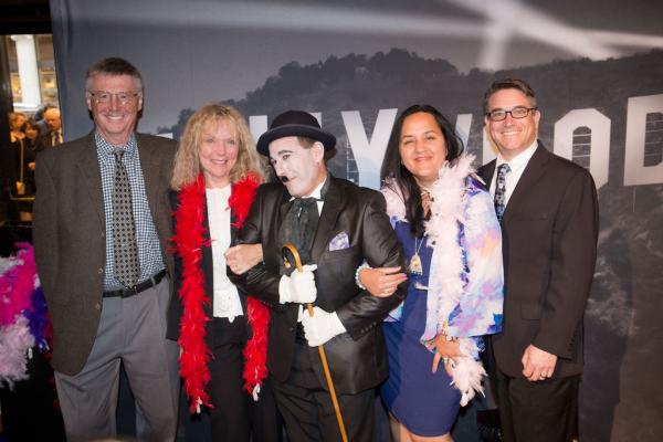 Spirit of Innovation Gala attendees with Charlie Chaplin impersonator in front of Hollywood sign backdrop