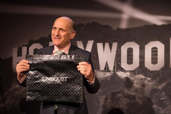 Spirit of Innovation Gala attendee in front of Hollywood sign backdrop holding a gift bag that reads, The Lundquist Institute