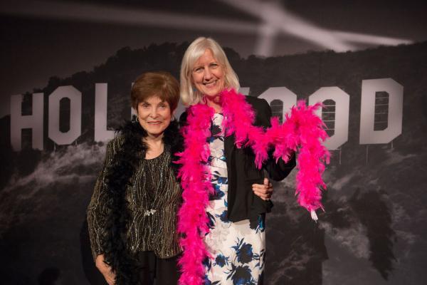 Spirit of Innovation Gala attendees in front of Hollywood sign backdrop holding a pink boa