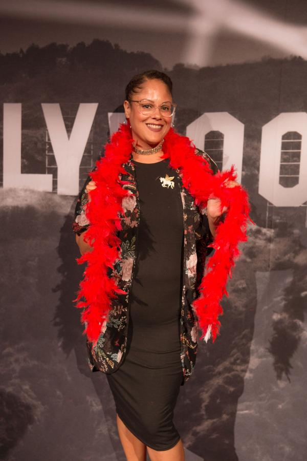 Spirit of Innovation Gala attendee in front of Hollywood sign backdrop holding a red boa