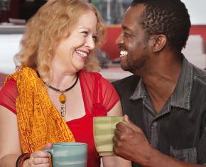 couple smiling at each other and holding coffee cups