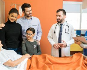 Family and two doctors at a patients bedside in hospital